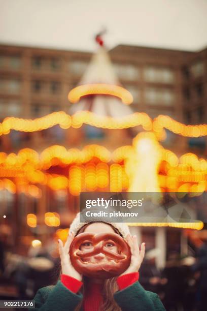 young woman with pretzel at christmas market - piskunov imagens e fotografias de stock