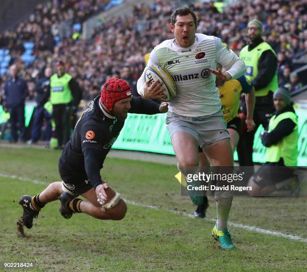 Alex Goode, the Saracens fullback breaks clear of James Haskell to score their second try during the Aviva Premiership match between Wasps and...