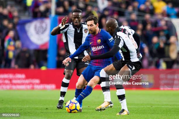 Lionel Messi of FC Barcelona conducts the ball between Emmanuel Boateng and Jefferson Lerma of Levante UD during the La Liga match between Barcelona...