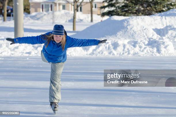 woman making arabesque while ice skating on an ice rink outdoors - figure skating lift stock pictures, royalty-free photos & images