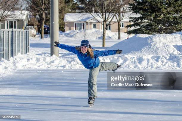 woman making arabesque while ice skating on an ice rink outdoors - figure skating lift stock pictures, royalty-free photos & images