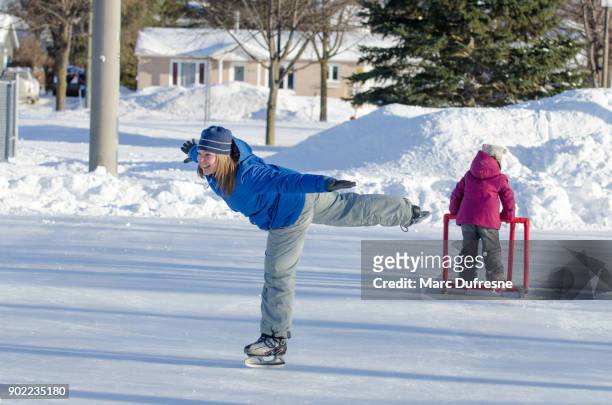 woman making arabesque while ice skating on an ice rink outdoors - dar uma ajuda imagens e fotografias de stock