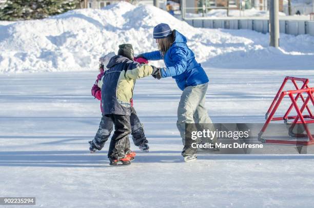 mamma höll hennes dotters och sons händer att hjälpa dem att skridskoåkning i cirkel - patins bildbanksfoton och bilder