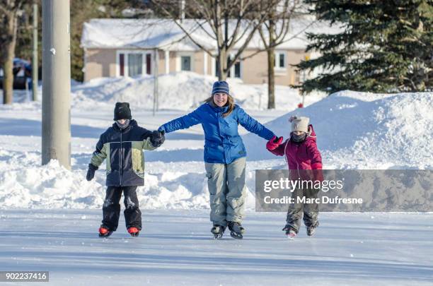 mamma höll hennes dotters och sons händer att hjälpa dem att skridskoåkning - patins bildbanksfoton och bilder