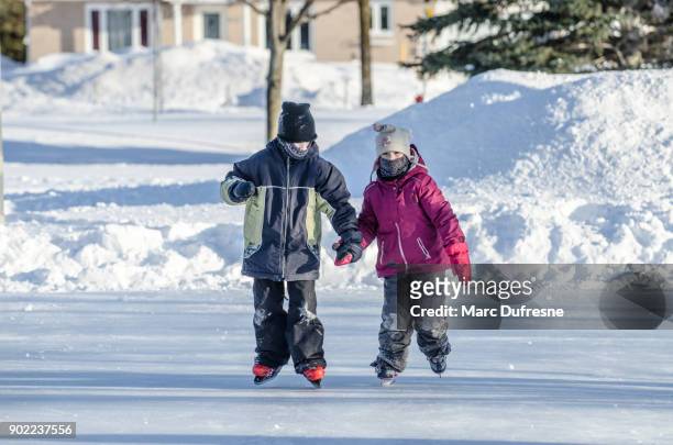 pojken håller hennes systers hand att hjälpa hennes skridskoåkning - patins bildbanksfoton och bilder
