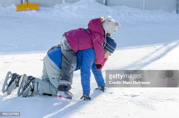flicka ha roligt genom att vara på mors tillbaka medan på hennes knän med ice skridskor på isbanan - patins bildbanksfoton och bilder