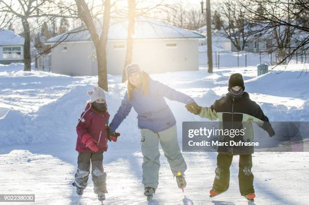 mamma höll hennes dotters och sons händer att hjälpa dem att skridskoåkning - patins bildbanksfoton och bilder