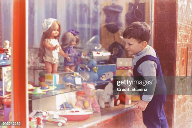 vintage niño mirando en la tienda del juguete - muñeca juguete fotografías e imágenes de stock