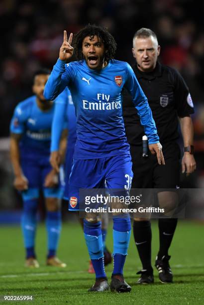Mohamed Elneny of Arsenal gestures with two fingers watched by referee Jonathan Moss during The Emirates FA Cup Third Round match between Nottingham...