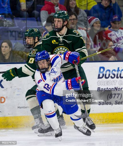 Liam Coughlin of the Vermont Catamounts checks Charlie Levesque of the Massachusetts Lowell River Hawks during NCAA men's hockey at the Tsongas...