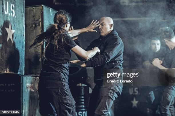 krav maga fighting group training in dark indoor urban setting - self defence stock pictures, royalty-free photos & images