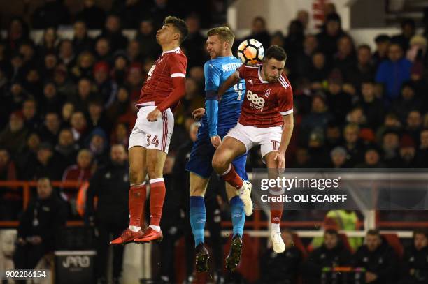 Arsenal's German defender Per Mertesacker vies with Nottingham Forest's English striker Tyler Walker and Nottingham Forest's English striker Ben...