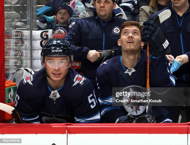 Marko Dano and Jack Roslovic of the Winnipeg Jets look on from the bench prior to puck drop against the San Jose Sharks at the Bell MTS Place on...