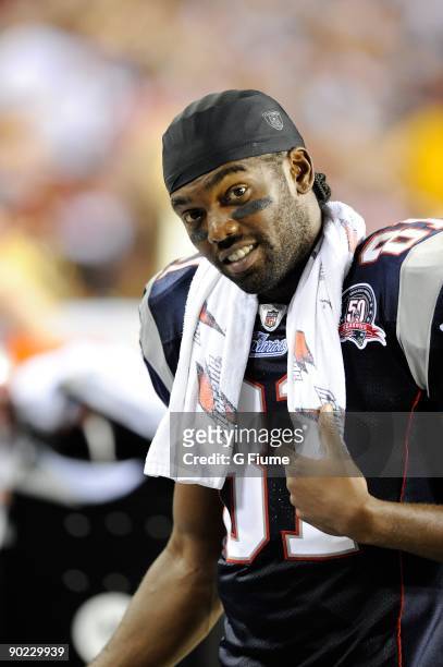 Randy Moss of the New England Patriots talks with teammates while on the sideline during a preseason game against the Washington Redskins at FedEx...