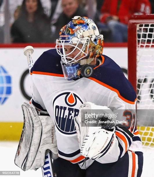 Cam Talbot of the Edmonton Oilers makes a save off of his face mask against the Chicago Blackhawks at the United Center on January 7, 2018 in...