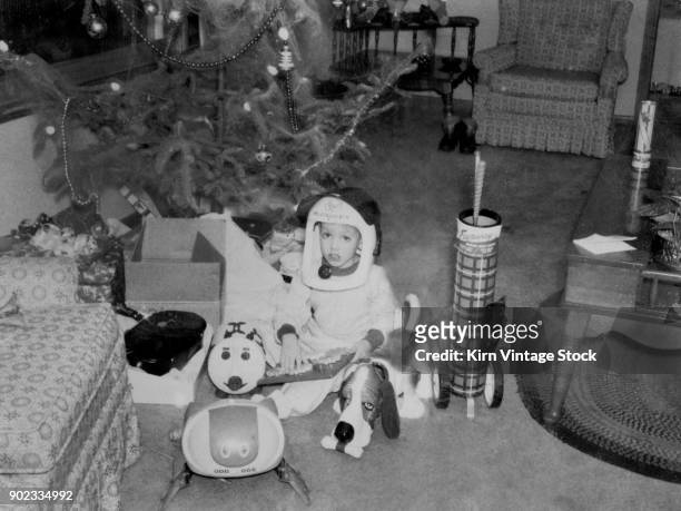 Boy sits among his gifts under the Christmas tree.