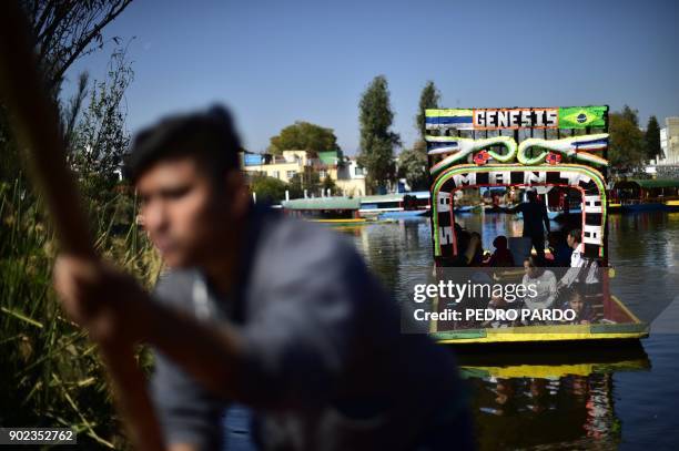 Rower and tourists are seen on board of "trajineras" -traditional flat-bottomed river boats- at Xochimilco natural reserve in Mexico City on January...