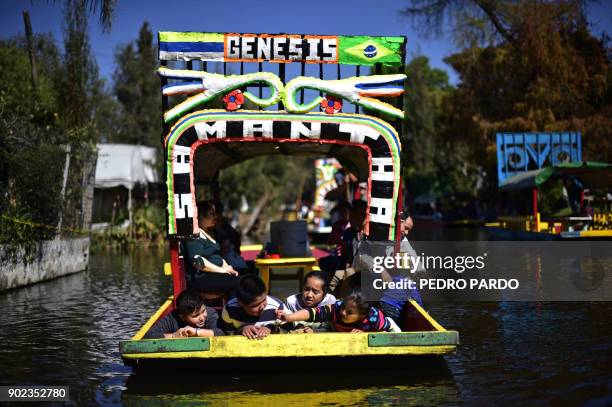 Children are seen on board of a "trajinera" -traditional flat-bottomed river boat- at Xochimilco natural reserve in Mexico City on January 7, 2018....
