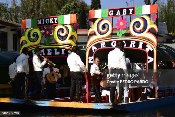 Mexican mariachis play on board of a moored "trajinera" -traditional flat-bottomed river boat- at Xochimilco natural reserve in Mexico City on...