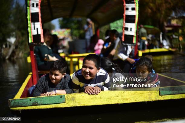 Children are seen on board of a "trajinera" -traditional flat-bottomed river boat- at Xochimilco natural reserve in Mexico City on January 7, 2018....