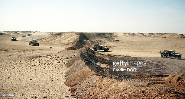 Convoy of M-998 high-mobility, multipurpose, wheeled vehicles drives past a berm as the 4th Battalion, 2nd Brigade move their camp near the border of...