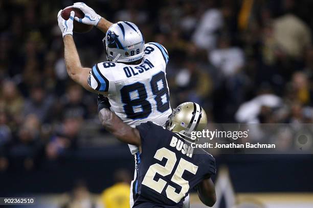 Greg Olsen of the Carolina Panthers catches the ball as Rafael Bush of the New Orleans Saints defends during the second half of the NFC Wild Card...