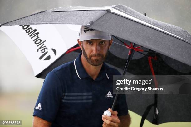 Dustin Johnson of the United States uses an umbrella as he walks to the 15th tee during the final round of the Sentry Tournament of Champions at...