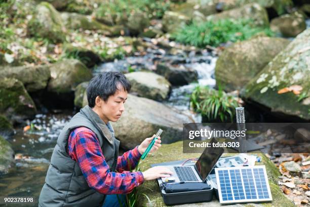 un ricercatore ambientale che monitora la qualità dell'acqua da un laboratorio sul campo ad energia solare - ambientalista foto e immagini stock
