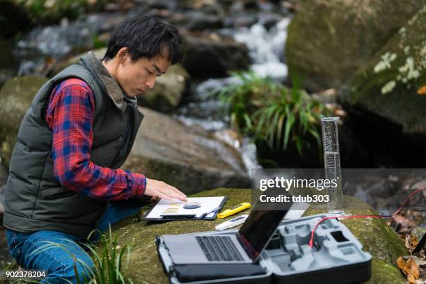 ein wissenschaftler, die überwachung der wasserqualität von einem solar betriebenen feldlabor - umweltschutzbeauftragter stock-fotos und bilder