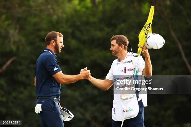 Dustin Johnson of the United States celebrates with his caddie and brother Austin on the 18th green after winning during the final round of the...