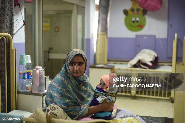 This picture taken on December 15, 2017 shows Sartaj holding her 15-days-old daughter Kinza, who is suffering from diarrhea and a blood infection, in...