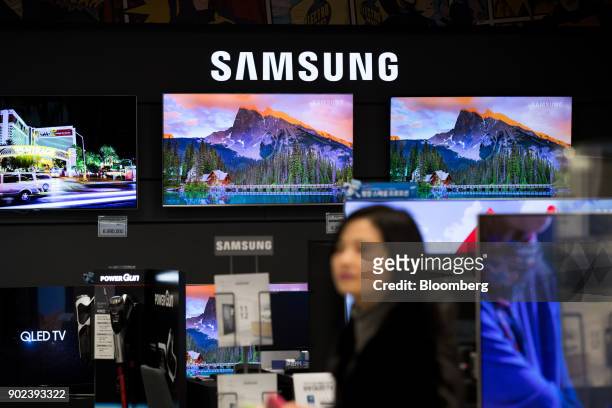 Customer walks past Samsung Electronics Co. Ultra High Definition televisions at an E-Mart Inc. Electro Mart store in Gimpo, South Korea, on Friday,...
