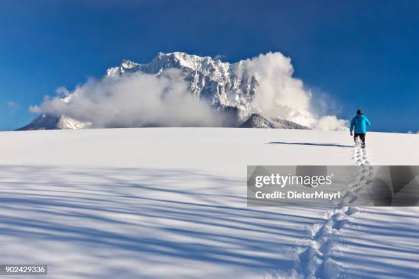 uomo che cammina nella neve di fronte al monte zugspitze - stato federato del tirolo foto e immagini stock