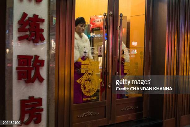 In this picture taken on January 7 a North Korean worker stands at the entrance of a North Korean restaurant located in one of China's largest Korea...