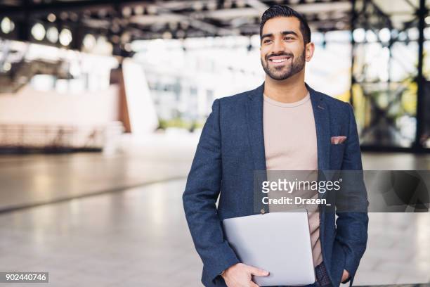 portrait of handsome indian guy with laptop - smart casual stock pictures, royalty-free photos & images