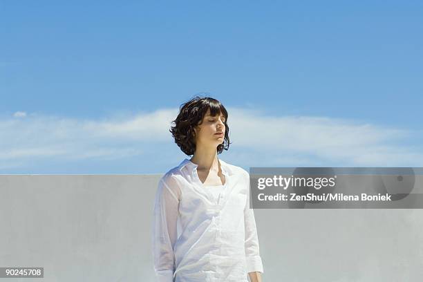 woman standing outdoors with eyes closed - blusa azul imagens e fotografias de stock