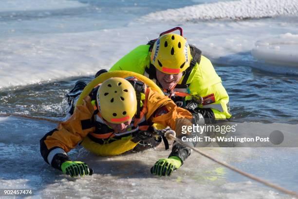 Firefighter Peter Slattery of the Arlington Swift Water Rescue Team practices an ice rescue on Steve Hendrix, a Washington Post reporter, in an inlet...