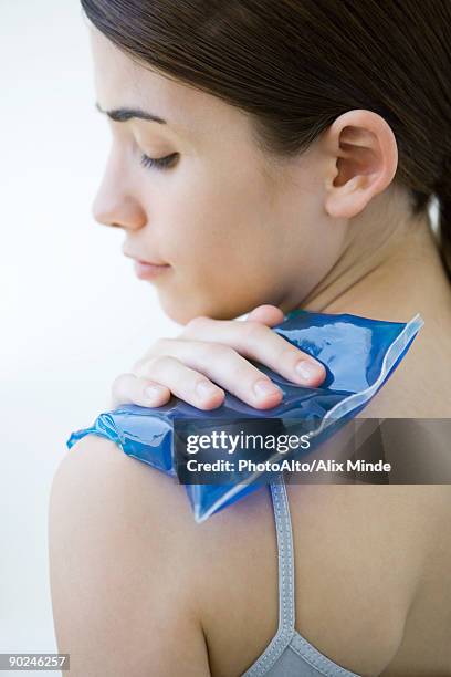 woman placing cold compress on shoulder, close-up - compresse stock-fotos und bilder