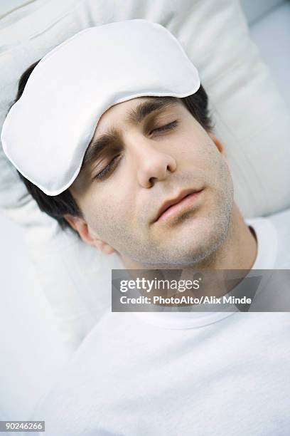 man reclining with ice pack on his forehead, eyes closed - compresse stock-fotos und bilder