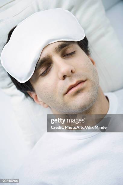 man reclining with ice pack on his forehead, eyes closed - ice pack stock pictures, royalty-free photos & images