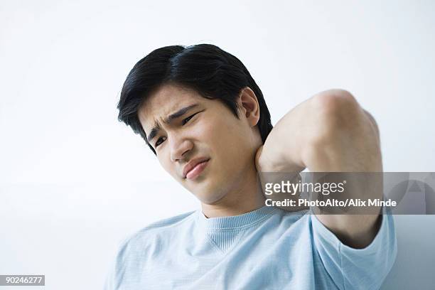 young man holding neck, furrowing brow - touching elbows stock pictures, royalty-free photos & images