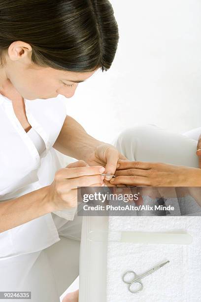 beautician giving a manicure, cropped view of woman's hand, high angle view - nail scissors stock pictures, royalty-free photos & images