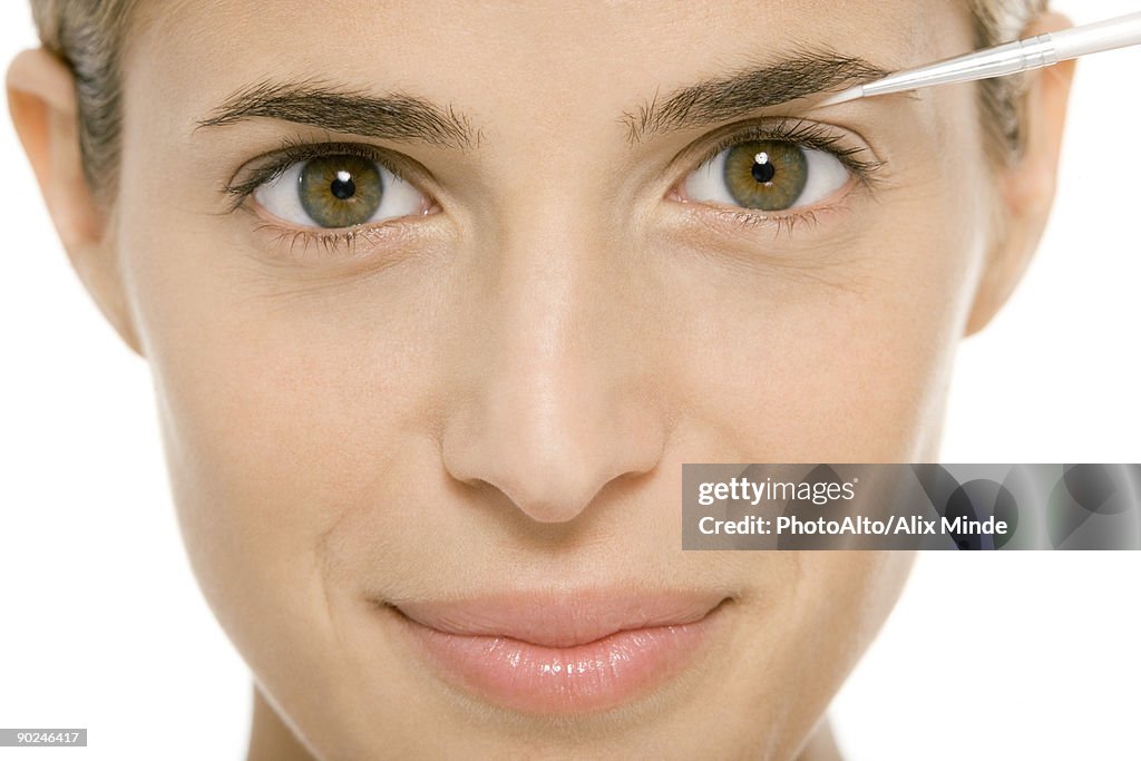 Woman applying make-up, smiling at camera