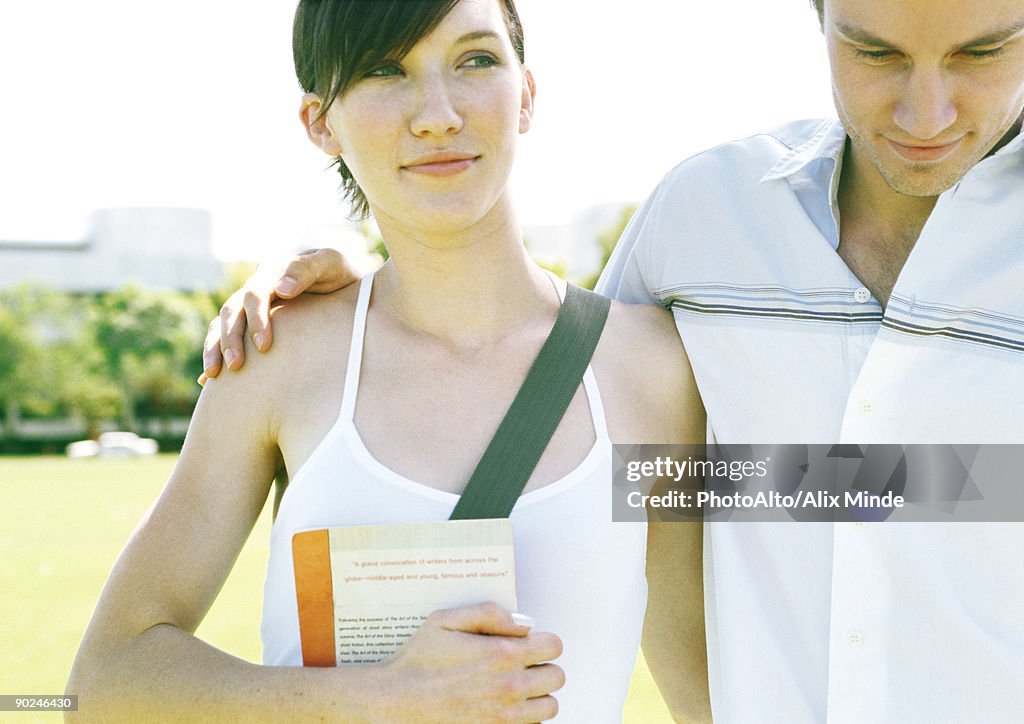 Young couple, man's arm around woman's shoulder