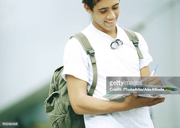 male student standing and writing on folder - strap stock pictures, royalty-free photos & images