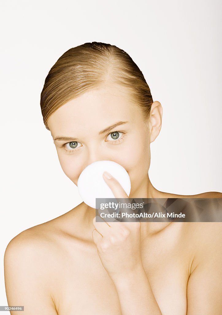 Woman holding up cotton pad in front of mouth