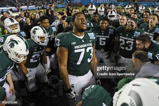 Michigan State Spartans players celebrate around tackle Dennis Finley on the field after the Spartans defeated Washington State Cougars 42 to 17 to...