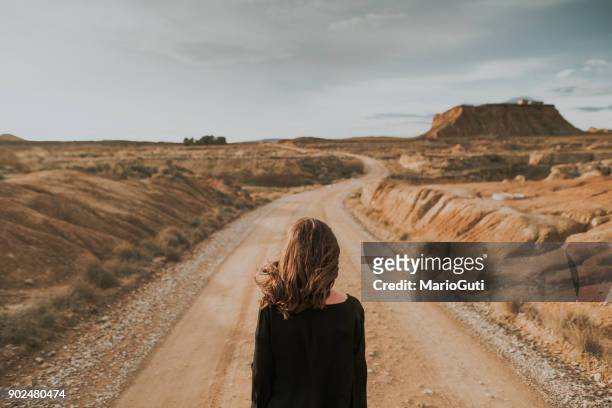 rear view of woman at desert road - arid climate stock pictures, royalty-free photos & images