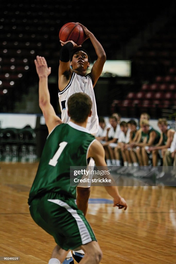 Black Male Basketball Player in White Gets Off Jump Shot