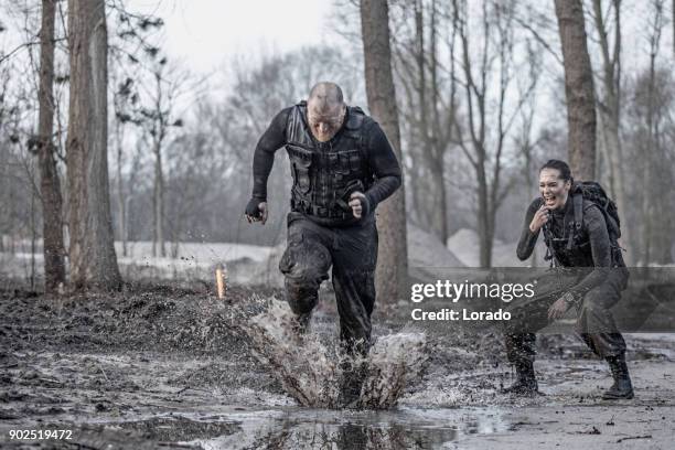 istruttore di esercitazioni femminile che adena soldato maschio rasato facendo sprint all'aperto nel fango - drill instructor foto e immagini stock